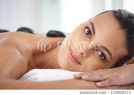 Portrait, hot stone and woman with massage for relaxing at spa for wellness, health and back treatment. Self care, cosmetic and female person with warm stone back therapy at natural beauty salon. Portrait, hot stone and woman with massage for relaxing at spa for wellness, health and back treatment. Self care, cosmetic and female person with warm stone back therapy at natural beauty salon. 139809515