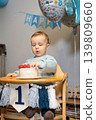 Toddler Baby boy eating berries from his birthday cake. First birthday family celebration. Child celebrates birthday with cake and decorations at home with balloons and decoration. Vertical card. 139809660