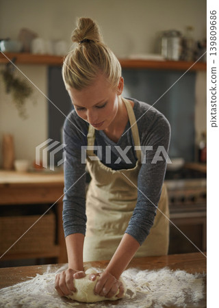 Woman, baking and calm in a kitchen with flour and dough for bread in a home. Food, cookies and cooking a dessert in a house with wheat powder, nutrition and lunch recipe on a table with a baker Woman, baking and calm in a kitchen with flour and dough for bread in a home. Food, cookies and cooking a dessert in a house with wheat powder, nutrition and lunch recipe on a table with a baker 139809686