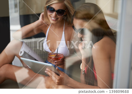 Tablet, friends or smile of women in bikini at patio of hotel on holiday, vacation or relax with cocktail. Swimsuit, technology and happy girls on internet, social media or reading magazine in summer Tablet, friends or smile of women in bikini at patio of hotel on holiday, vacation or relax with cocktail. Swimsuit, technology and happy girls on internet, social media or reading magazine in summer 139809688