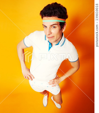 Studio, portrait and man in retro tennis uniform with confidence, smile and high angle. Gym, club and happy athlete in vintage sports fashion on orange background with pride, game and sportswear. 139810018