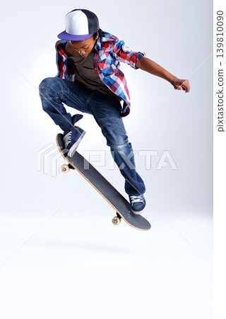 Skateboard trick, jump or African kid in studio with trendy fashion, skill or mockup space with cool style. Skater, performance or young child skateboarding with energy isolated on white background Skateboard trick, jump or African kid in studio with trendy fashion, skill or mockup space with cool style. Skater, performance or young child skateboarding with energy isolated on white background 139810090