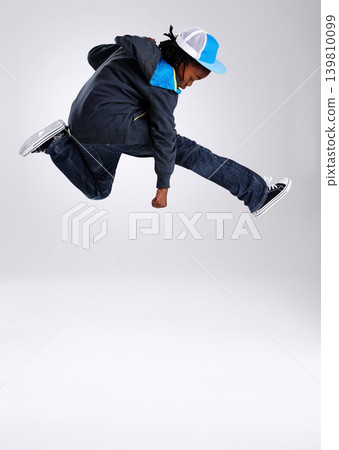 Child, jump and dancing with hiphop and street style clothing in a studio with boy dancer. Trendy, energy and cool African kid with youth and rap music with white background and gen z clothes Child, jump and dancing with hiphop and street style clothing in a studio with boy dancer. Trendy, energy and cool African kid with youth and rap music with white background and gen z clothes 139810099