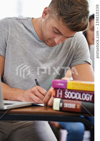 Student at a desk, man and writing with textbooks, education and knowledge with exams and test. Person, college and guy with ideas and laptop with inspiration and studying with learning or university Student at a desk, man and writing with textbooks, education and knowledge with exams and test. Person, college and guy with ideas and laptop with inspiration and studying with learning or university 139810339