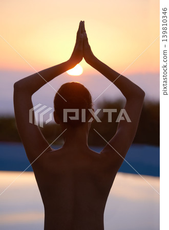Tree, yoga and woman meditate at sunset by swimming pool for healthy body, wellness and zen outdoor. Rear view, vrikshasana pose and person at water at twilight to relax, peace or calm for balance Tree, yoga and woman meditate at sunset by swimming pool for healthy body, wellness and zen outdoor. Rear view, vrikshasana pose and person at water at twilight to relax, peace or calm for balance 139810346
