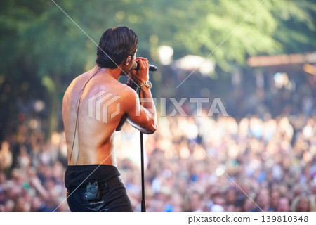 Singer, man and performance at music concert, festival or party with crowd of people. Rock, celebration and musician on stage for show, talent or back of artist on microphone outdoor for social event Singer, man and performance at music concert, festival or party with crowd of people. Rock, celebration and musician on stage for show, talent or back of artist on microphone outdoor for social event 139810348