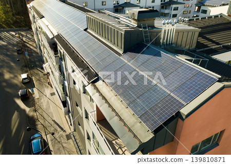 Aerial view of solar photovoltaic panels on a roof top of residential building block for producing clean electric energy. Autonomous housing concept. Aerial view of solar photovoltaic panels on a roof top of residential building block for producing clean electric energy. Autonomous housing concept. 139810871