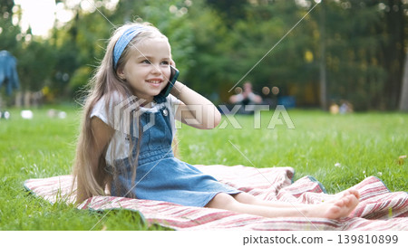 Pretty little child girl having conversation on her mobile phone in summer park. Pretty little child girl having conversation on her mobile phone in summer park. 139810899
