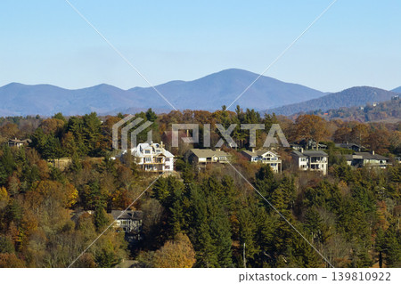 Aerial view of big family houses on mountain top between yellow trees in North Carolina suburban area in fall season. Real estate development in american suburbs Aerial view of big family houses on mountain top between yellow trees in North Carolina suburban area in fall season. Real estate development in american suburbs 139810922