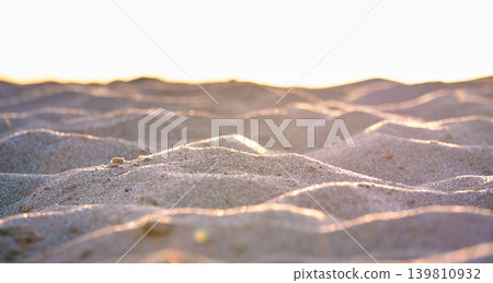 Close up of clean yellow sand surface covering seaside beach illuminated with evening light. Travel and vacations concept Close up of clean yellow sand surface covering seaside beach illuminated with evening light. Travel and vacations concept 139810932
