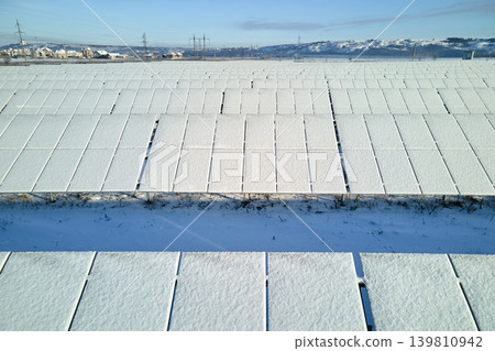 Aerial view of sustainable electrical power plant with solar photovoltaic panels covered with snow in winter for producing clean energy. Concept of low effectivity of renewable electricity in north Aerial view of sustainable electrical power plant with solar photovoltaic panels covered with snow in winter for producing clean energy. Concept of low effectivity of renewable electricity in north 139810942