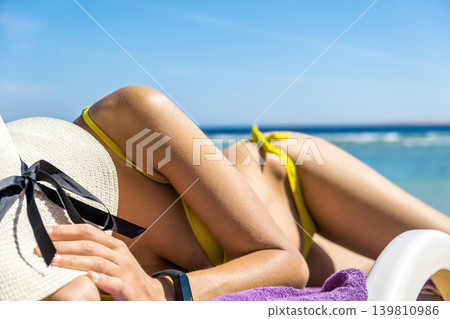 Close up of young woman hip and shoulder laying on beach chair at sea shore sunbathing. 139810986