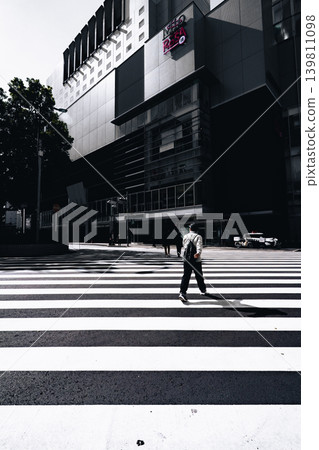 A person crossing a pedestrian crossing; a monochrome urban landscape of Chiba City. A person crossing a pedestrian crossing; a monochrome urban landscape of Chiba City. 139811098