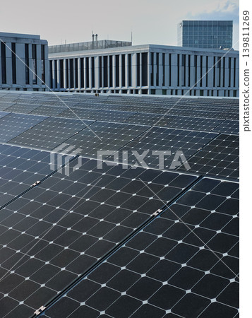 Solar panels cover urban rooftop with modern office buildings in background under sky Solar panels cover urban rooftop with modern office buildings in background under sky 139811269