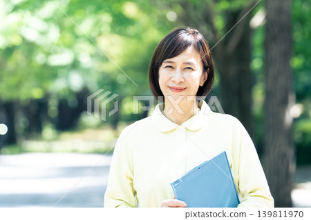 一位女性護理員在戶外拿著一個活頁夾。 一位女性護理員在戶外拿著一個活頁夾。 139811970