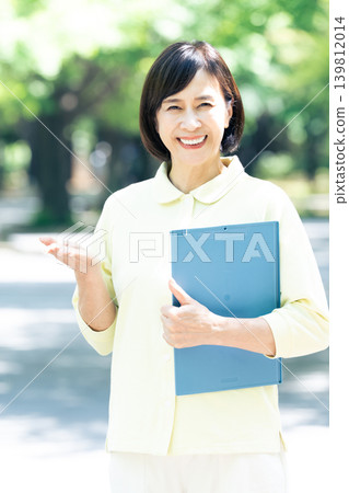 一位女性護理員在戶外拿著一個活頁夾。 139812014