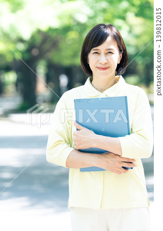 一位女性護理員在戶外拿著一個活頁夾。 139812015