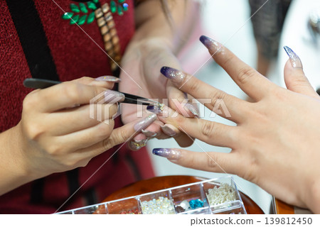 Professional nail technician applying crystal decoration on glossy gradient manicure in beauty salon closeup elegant long nails self care lifestyle Professional nail technician applying crystal decoration on glossy gradient manicure in beauty salon closeup elegant long nails self care lifestyle 139812450