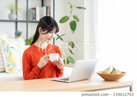 在客廳裡使用電腦的中年婦女 在客廳裡使用電腦的中年婦女 139812703