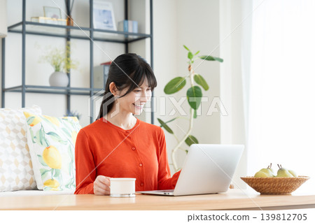 在客廳裡使用電腦的中年婦女 在客廳裡使用電腦的中年婦女 139812705