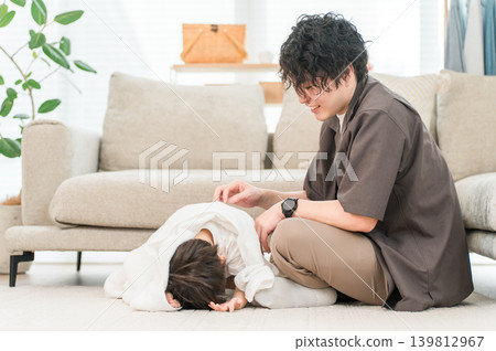 After a bath, a father dries his child with a towel (the child is in the "terrible twos" stage and is reluctant). 139812967