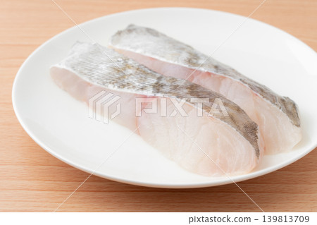 Close-up of a slice of cod (uncooked) on a plate. Close-up of a slice of cod (uncooked) on a plate. 139813709