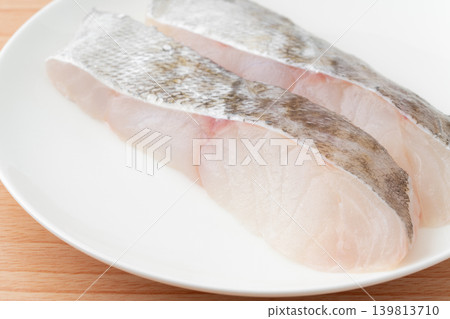 Close-up of a slice of cod (uncooked) on a plate. Close-up of a slice of cod (uncooked) on a plate. 139813710