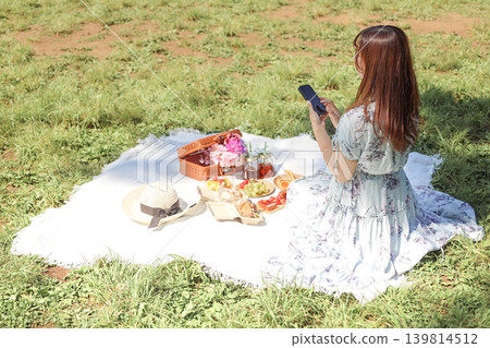 A woman taking picnic photos with her smartphone. A woman taking picnic photos with her smartphone. 139814512
