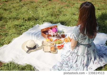 A woman's back as she enjoys a picnic in the park. A woman's back as she enjoys a picnic in the park. 139814513