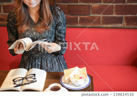 Adult woman reading a book and drinking coffee at a cafe Adult woman reading a book and drinking coffee at a cafe 139814516