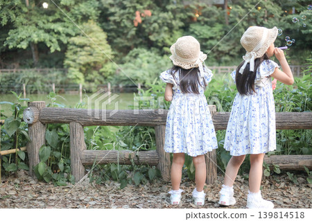 夏日公園裡,兩姊妹正在玩肥皂泡,她們的背影清晰可見。 夏日公園裡,兩姊妹正在玩肥皂泡,她們的背影清晰可見。 139814518