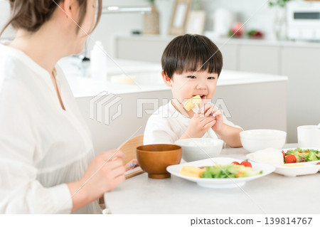 一個男孩和他的媽媽一起吃飯。 一個男孩和他的媽媽一起吃飯。 139814767