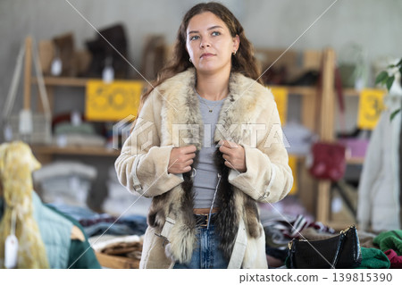 Young woman trying on fur coat in store Young woman trying on fur coat in store 139815390