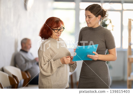 Female secretary or social worker talk with woman in reception area Female secretary or social worker talk with woman in reception area 139815403