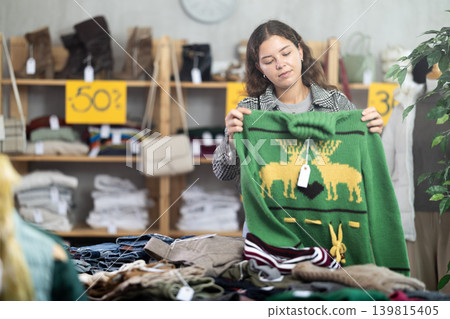 Young woman chooses sweater in clothing store Young woman chooses sweater in clothing store 139815405