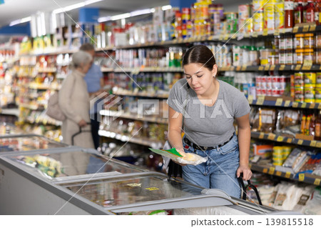 Young girl looking at foods in glass refrigerated display case Young girl looking at foods in glass refrigerated display case 139815518