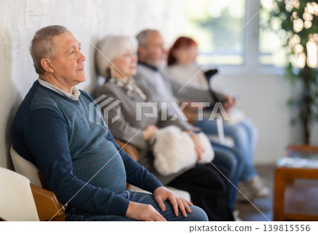 Group of elderly people sitting in chairs in queue to see doctor in lobby medical facility 139815556