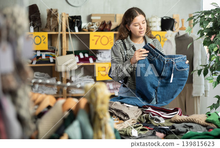 Young woman choosing jeans in clothing store Young woman choosing jeans in clothing store 139815623