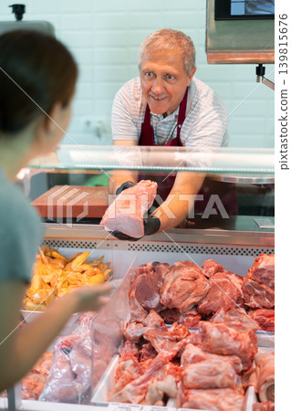Adult man butcher sells chicken in butcher shop Adult man butcher sells chicken in butcher shop 139815676