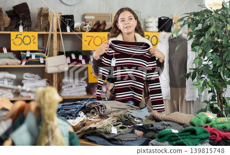 Young woman chooses sweater in clothing store Young woman chooses sweater in clothing store 139815748