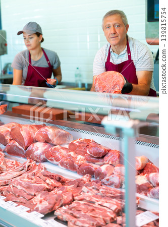 Male farmer of meat products in butcher shop offers to buy fresh beef tenderloin. Male farmer of meat products in butcher shop offers to buy fresh beef tenderloin. 139815754