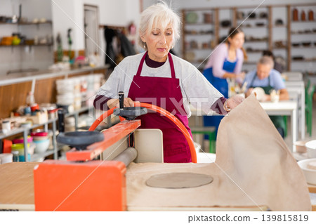 lady is working with machine clay press Roller lady is working with machine clay press Roller 139815819