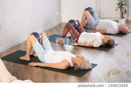 Group of elderly people doing pilates with soft ball in studio Group of elderly people doing pilates with soft ball in studio 139815840