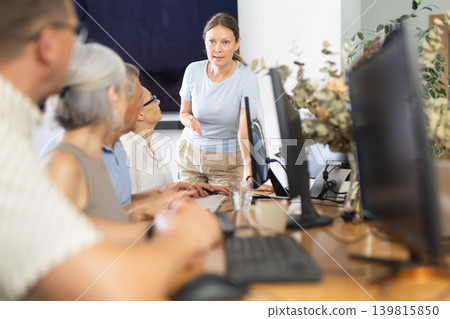 Female teacher conducting group lesson of computer skills to older people Female teacher conducting group lesson of computer skills to older people 139815850