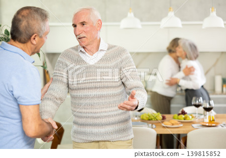 Two elderly men shaking hands in kitchen Two elderly men shaking hands in kitchen 139815852