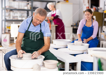 Mature male artist making pottery in studio 139815980