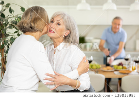 Two elderly women friends hugging in kitchen Two elderly women friends hugging in kitchen 139815985