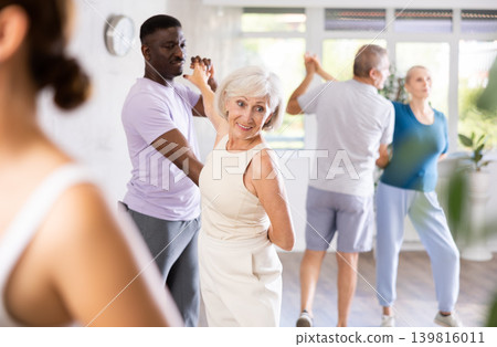 African American dancing bachata with senior female partner during group class African American dancing bachata with senior female partner during group class 139816011