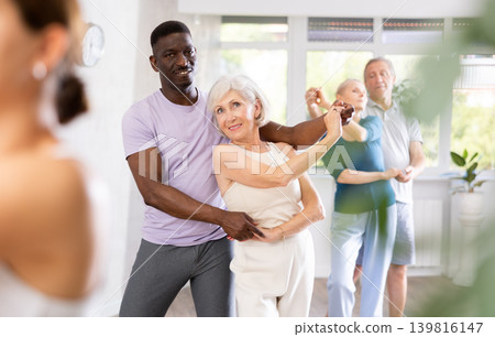 African-American man dances steamy salsa with elderly female companion for fitness classes African-American man dances steamy salsa with elderly female companion for fitness classes 139816147
