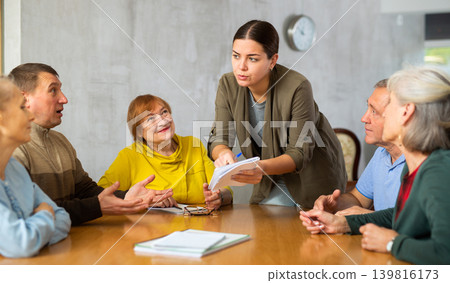 Young psychologist together with elderly adults have group therapy round table 139816173